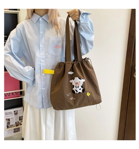 Detailansicht der dunkelbraunen Segeltuchtasche mit Kuh-Stickerei und Kordelzugverschluss