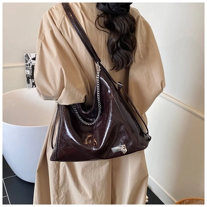 Detail of glossy brown leather tote bag with silver chain and heart lock charm