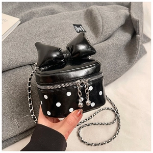 Close-up of a mini crossbody bag with a large bow and white polka dots on black leather