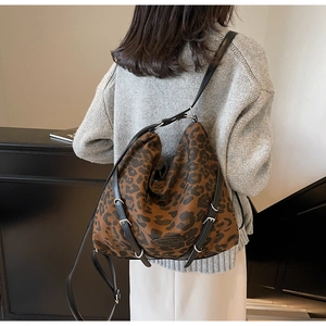 Close-up of leopard print hobo bag showing adjustable metal buckles and leather brand logo