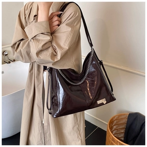 Close-up of vintage glossy dark brown tote bag with silver chain and heart lock detail