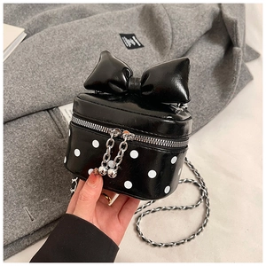 Detailed shot of a black mini polka dot crossbody bag featuring a large decorative bow