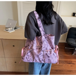 Détail du sac cabas tie-dye violet avec rubans roses et finitions métalliques