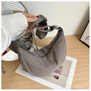 Detail of taupe nylon crescent bag with adjustable strap on a wooden table setup