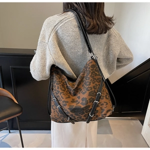 Close-up of leopard print canvas hobo bag showing leather strap and brand logo detail