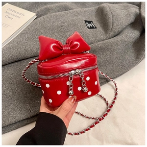 Detailed view of red polka dot mini bag with a large bow and silver chain strap