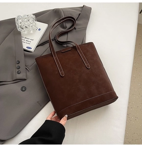 Detail of dark brown matte texture tote bag with elegant long handles and visible stitching