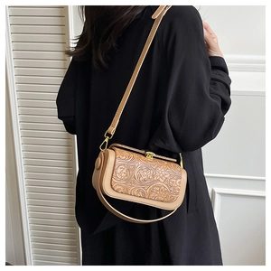 Detail of vintage embossed floral pattern on a beige handbag with a gold metal clasp