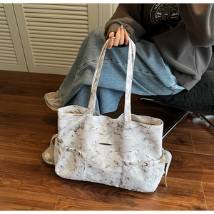 Détail du grand sac cabas motif marbre blanc avec cordons et plaque logo métallique