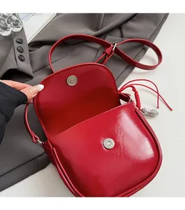 Détail du mini sac selle rouge avec fermoir magnétique et pendentif en métal