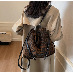 Detail of leopard print tote bag with black leather strap and metallic buckle accents