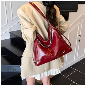 Close-up of deep red patent leather tote bag featuring glossy finish and silver chain detail