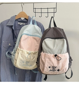 Detail of color-block backpack showing water-resistant nylon fabric and front drawstring pocket