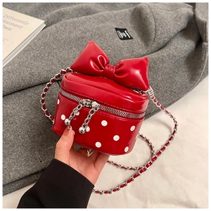 Detailed view of red polka dot mini bag with oversized bow and silver chain strap