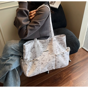 Détail du grand sac cabas à motif marbre avec plaque métallique et poches latérales à cordon