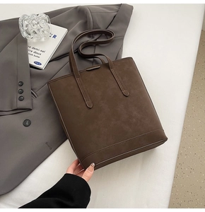 Detailed view of dark brown minimalist tote bag with matte leather texture and stitching