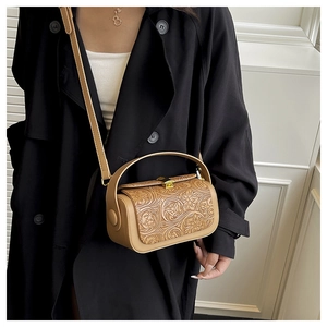 Detailed view of floral embossed shoulder bag worn by model in warm khaki tone