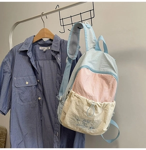 Detail of multi-color nylon backpack featuring star embroidery and drawstring closure