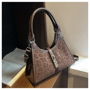 Detail of leopard print bucket bag with silver metal lock on a rustic wooden table