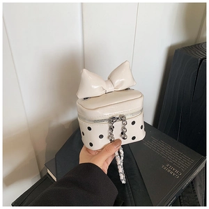 Macro shot of cream mini polka dot square bag with large bow and silver chain strap