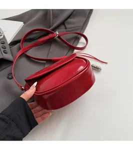 Détail d'un sacoche rouge en cuir verni avec pendentif cacahuète et bandoulière réglable
