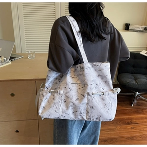 Vue détaillée du sac cabas marbré blanc avec deux poches à cordon et bandoulière longue
