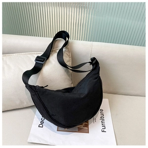Detail of black crescent nylon shoulder bag on sofa with stylish magazine background