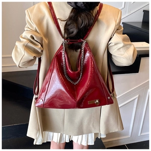 Close-up of wine red patent leather tote bag with silver chain and heart charm