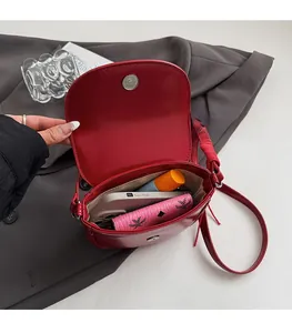 Vue détaillée de l'intérieur du sac selle rouge en cuir contenant des essentiels