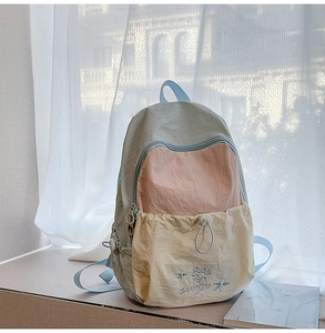 Detail of multi-color nylon backpack featuring drawstring pocket and sun embroidery