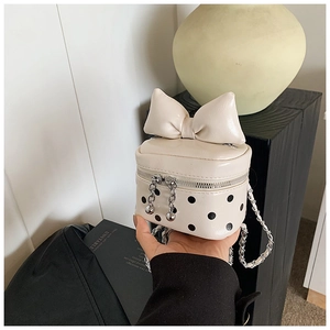 Detail of off-white polka dot mini bag featuring large leather bow and silver chain strap