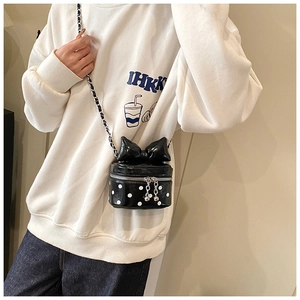 Close-up of mini polka dot cylindrical bag featuring a large bow and metal chain strap