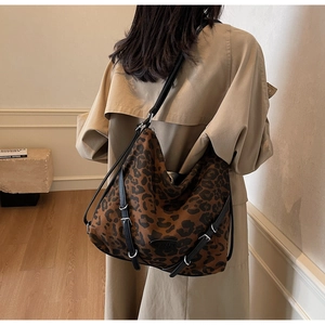 Close-up of leopard print tote bag featuring black leather straps and silver buckle detail