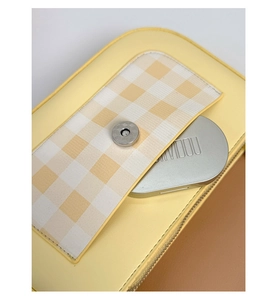 Détail du sac bandoulière jaune avec rabat en tissu écossais et fermoir magnétique