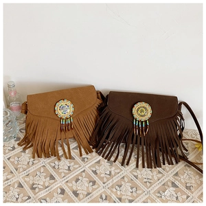 Detail of bohemian suede crossbody bags with colorful beaded disks and long fringe tassels