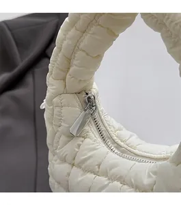 Detailed close-up of smooth metal zipper and quilted texture on white hobo bag