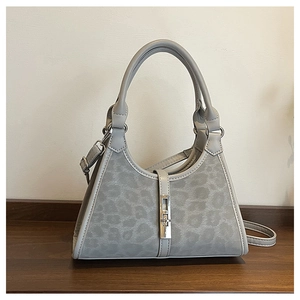 Detail view of grey leopard print bucket bag with silver twist lock and round top handle