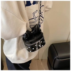 Detail of mini black polka dot crossbody bag with a large bow and silver chain strap