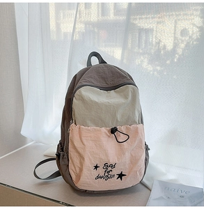 Detailed view of color-block nylon backpack with drawstring pocket and printed text
