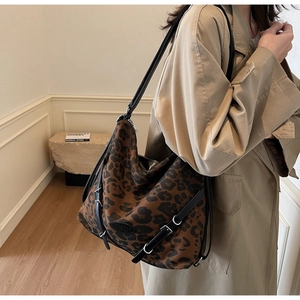 Macro detail of large leopard print tote bag with black leather strap and silver buckles