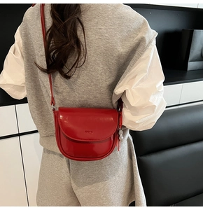 Détail d'un sac besace rouge verni avec pendentif argenté et fine bandoulière
