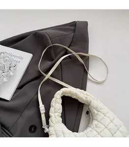 Detail of adjustable shoulder strap and metal zipper on white quilted bubble handbag