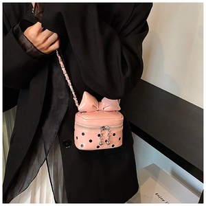 Detailed view of a pink polka dot mini crossbody bag with a large bow on a black blazer