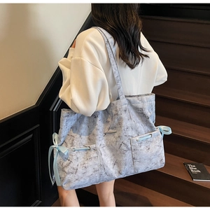 Détail du sac cabas à motif marbre avec cordons en ruban bleu et poches extérieures