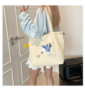 Detail der cremefarbenen Canvas-Tragetasche mit Hai-Stickerei und Good Luck Text
