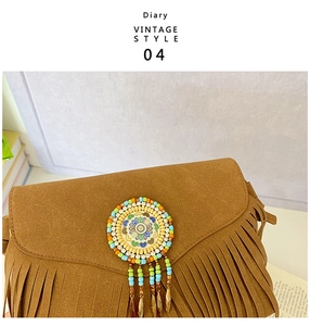 Détail macro du sac en daim marron avec cercle de perles bohèmes et longues franges