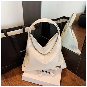 Detailed shot of white glossy tote bag featuring a silver chain and heart charm accessory