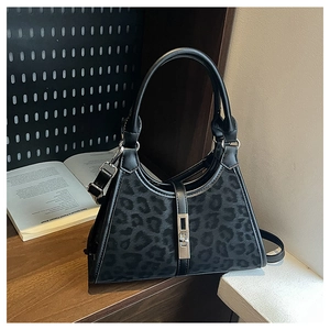 Detail of black leopard print bucket bag with metal clasp and leather top handle