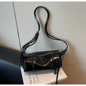 Detail of black glossy cylindrical shoulder bag texture on decorative books