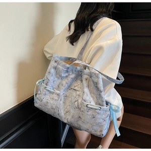 Détail du sac cabas marbré bleu clair avec des accents de ruban élégants sur le côté
